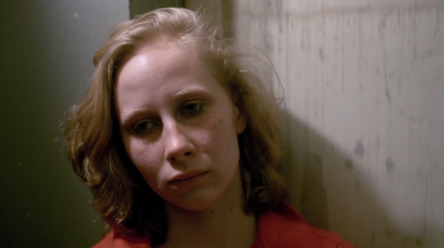 Woman working in a supermarket rides an elevator with a forlorn expression